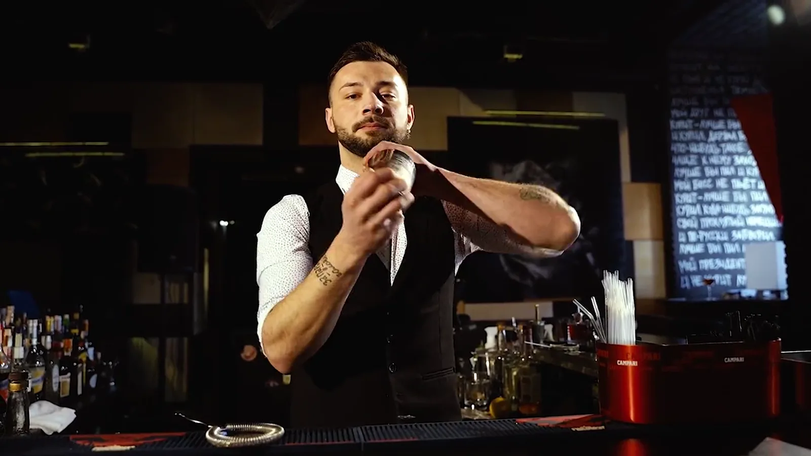 Un bartender preparando un cóctel con sus utensilios de barra